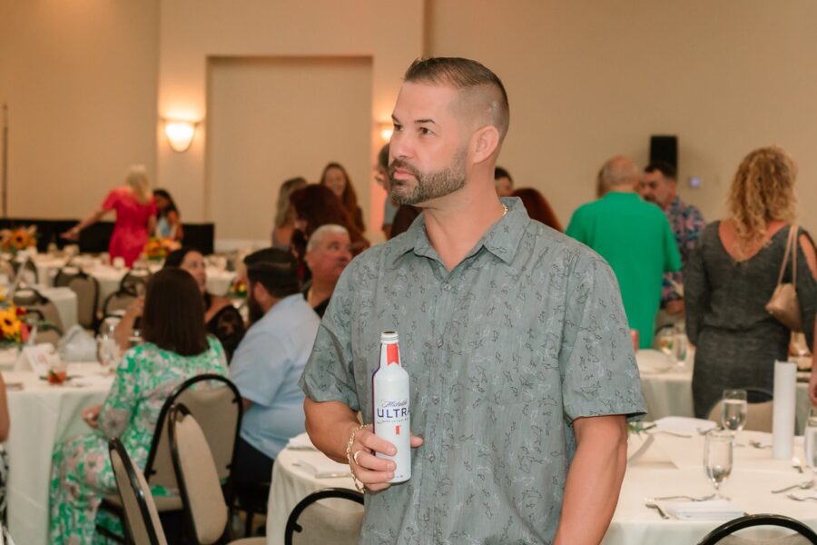 a man holding a bottle of wine in a room full of people