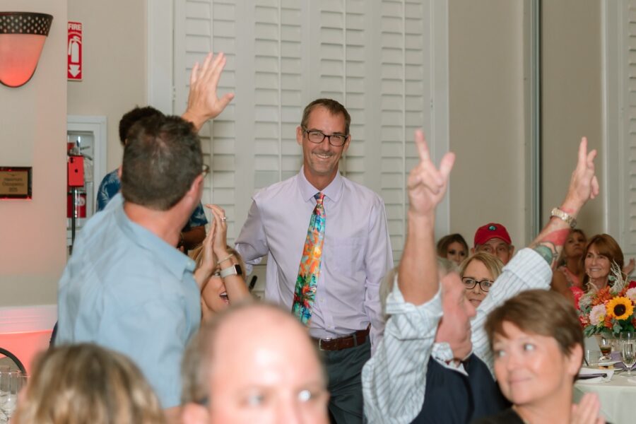 a group of people sitting around a table with their hands in the air