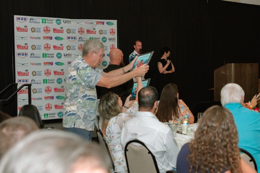 a group of people sitting at tables in front of a microphone