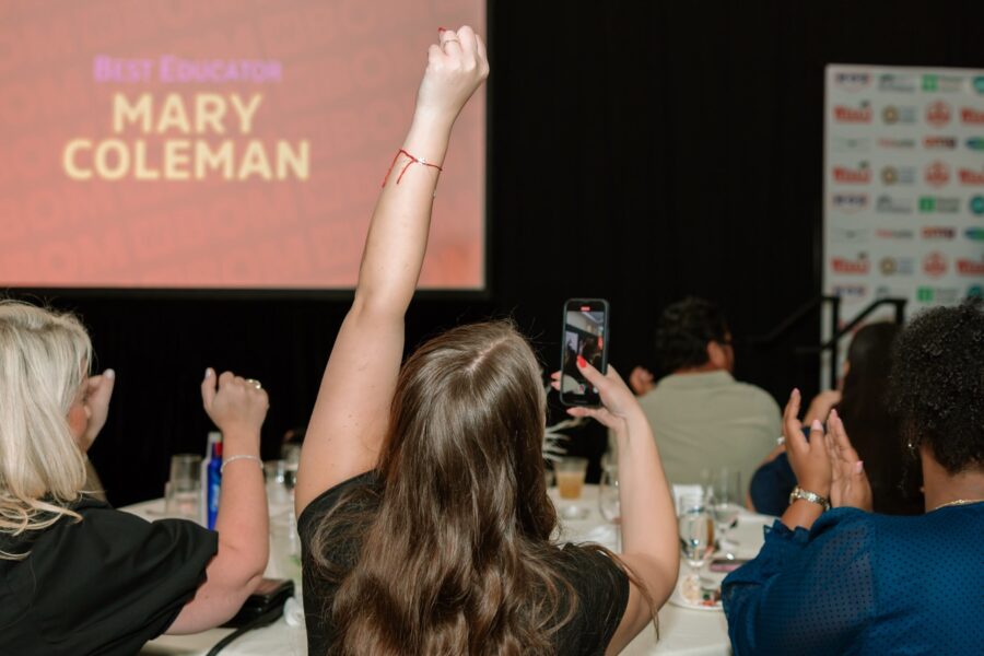 a group of people sitting at a table with their hands in the air