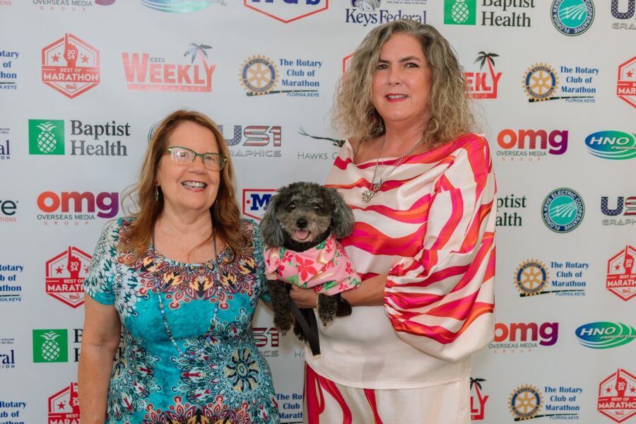 two women standing next to each other holding a dog