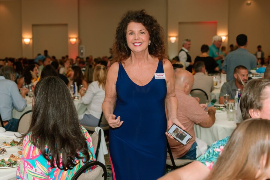 a woman in a blue dress standing in a room full of people