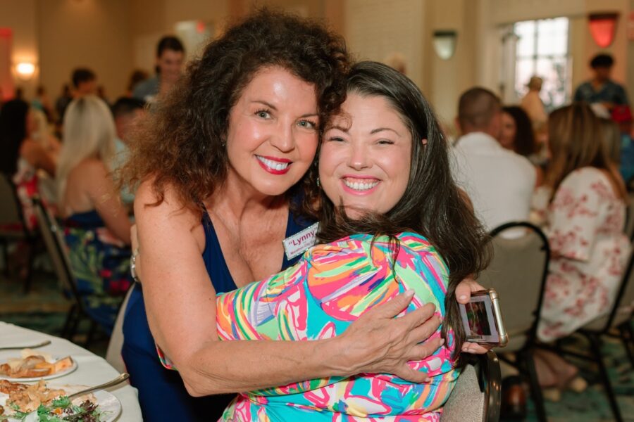 two women hugging each other at a banquet