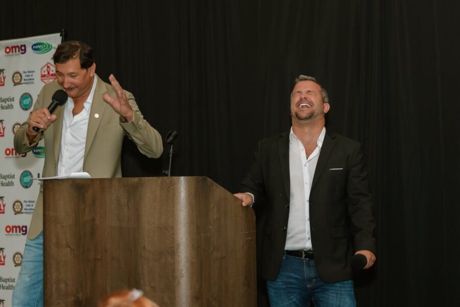 two men standing at a podium with their hands in the air