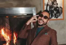 a man sitting in front of a fire place talking on a cell phone