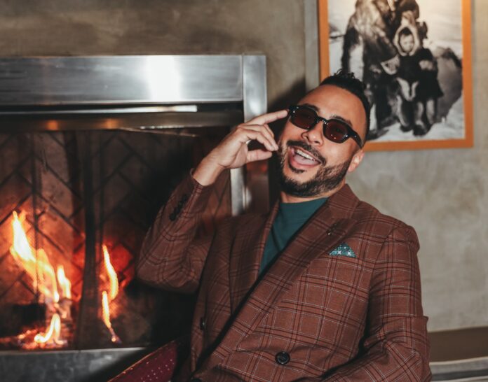 a man sitting in front of a fire place talking on a cell phone