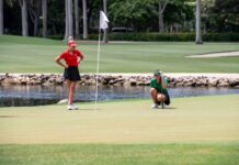 a woman in a red shirt is playing golf