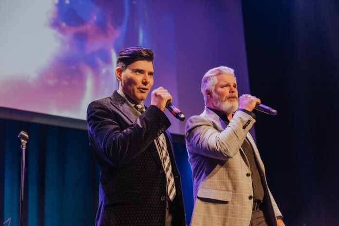 two men standing next to each other on a stage