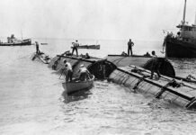 a group of men standing on top of a boat in the water