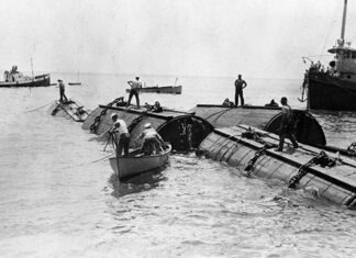 a group of men standing on top of a boat in the water