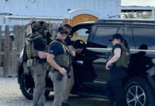 a group of men standing next to a black suv