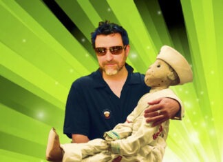 a man holding a stuffed animal in front of a green background