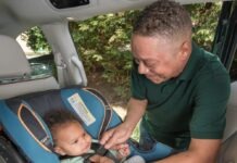 a man sitting in a car seat with a baby in it