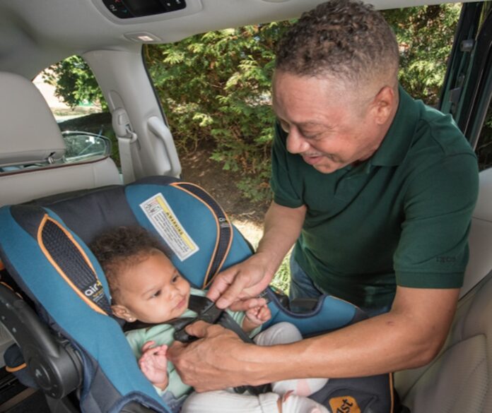 a man sitting in a car seat with a baby in it