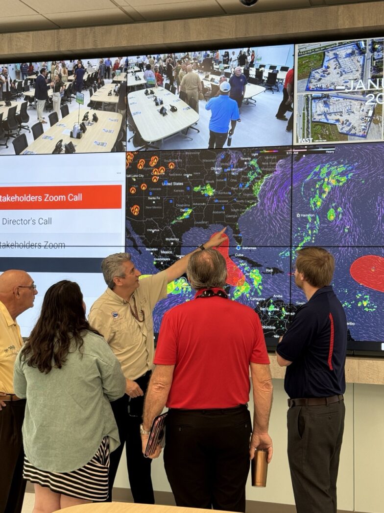 a group of people standing in front of a large screen