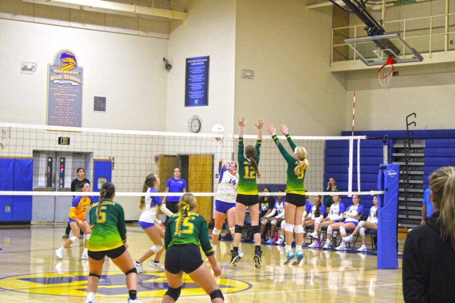 a group of girls playing volleyball in a gym