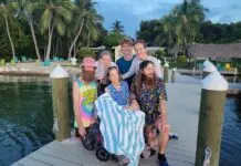 a group of people sitting on a dock next to a body of water