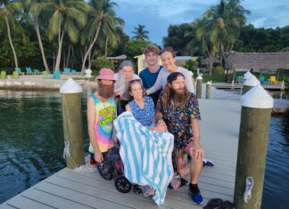 a group of people sitting on a dock next to a body of water