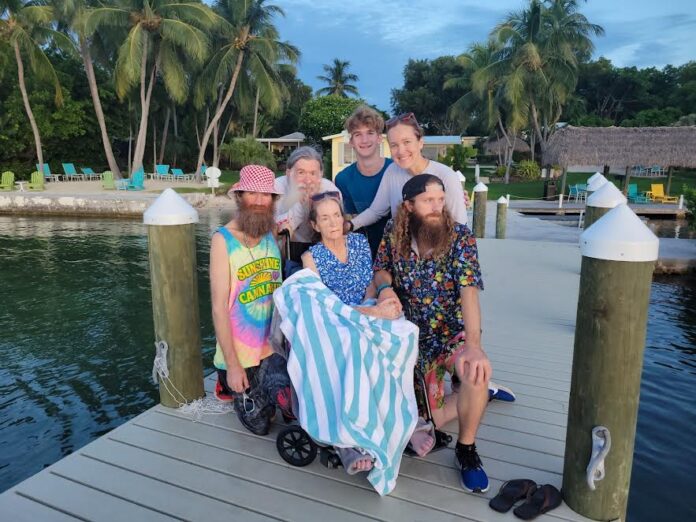 a group of people sitting on a dock next to a body of water