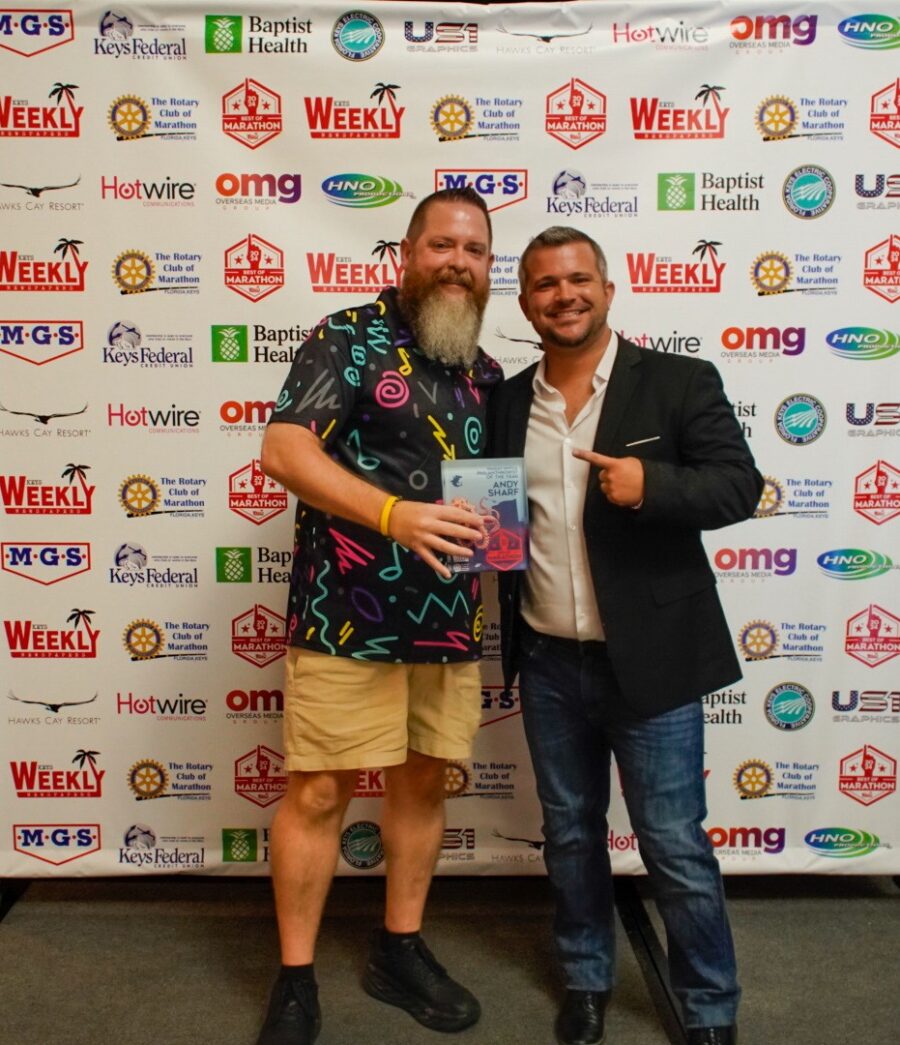 two men standing next to each other in front of a sign