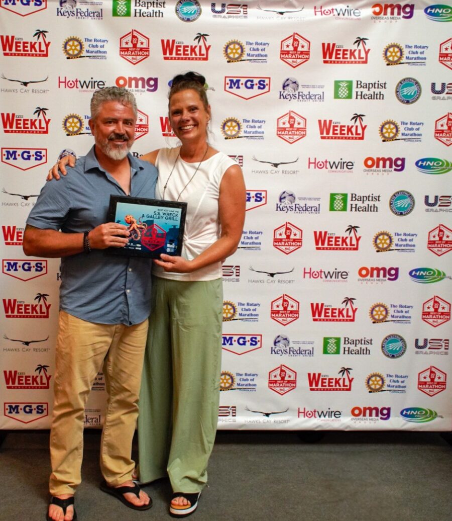 a man standing next to a woman holding a plaque