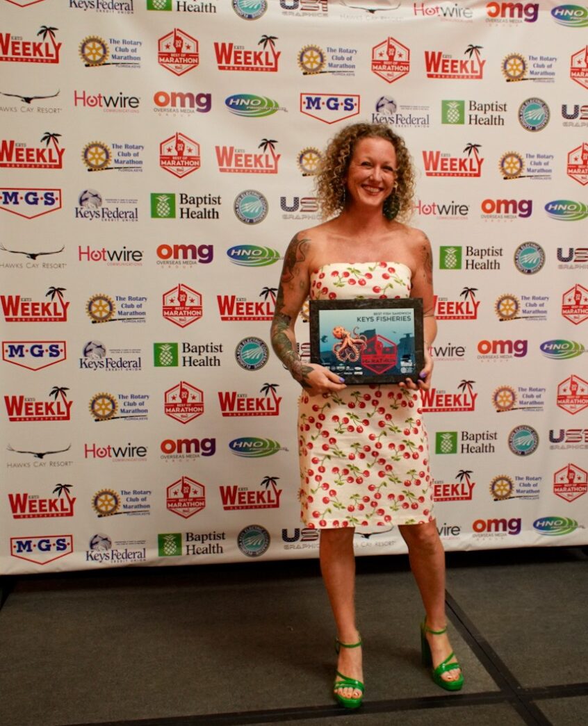 a woman standing in front of a wall holding a plaque