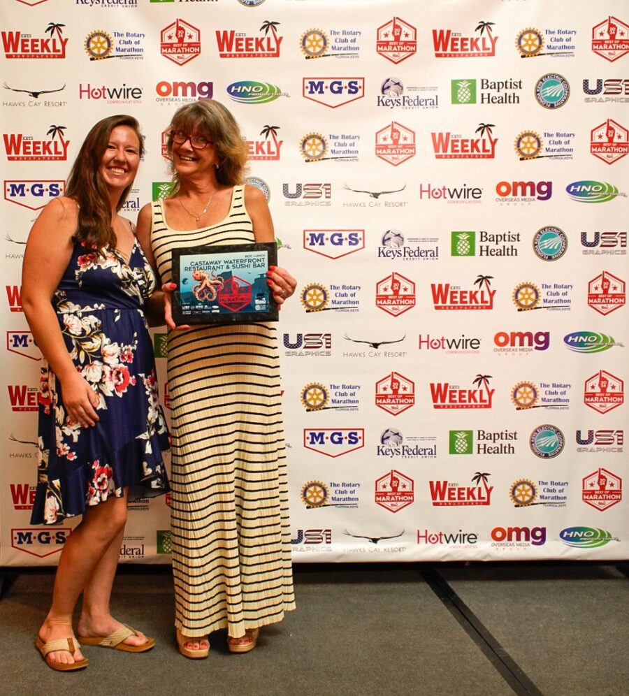 two women standing next to each other in front of a banner