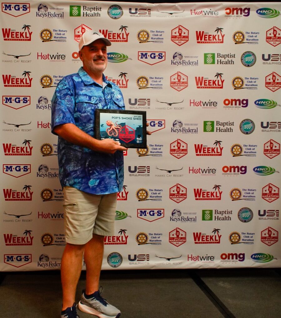 a man standing in front of a wall holding a plaque