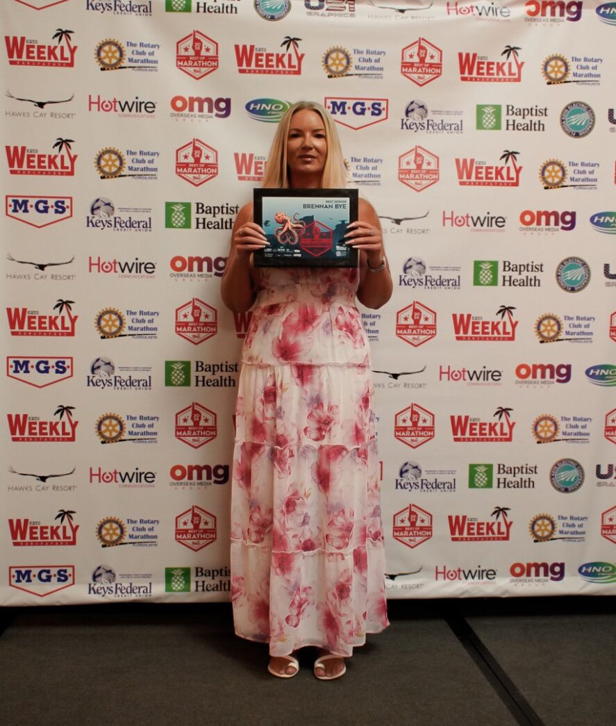 a woman standing in front of a wall holding a plaque