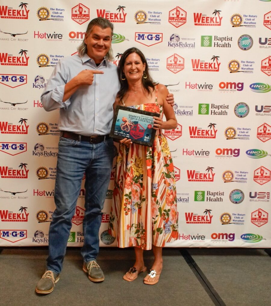 a man standing next to a woman holding an award