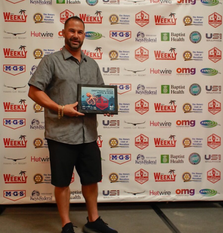 a man standing in front of a wall holding a plaque