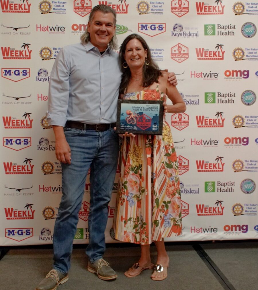 a man standing next to a woman holding a plaque