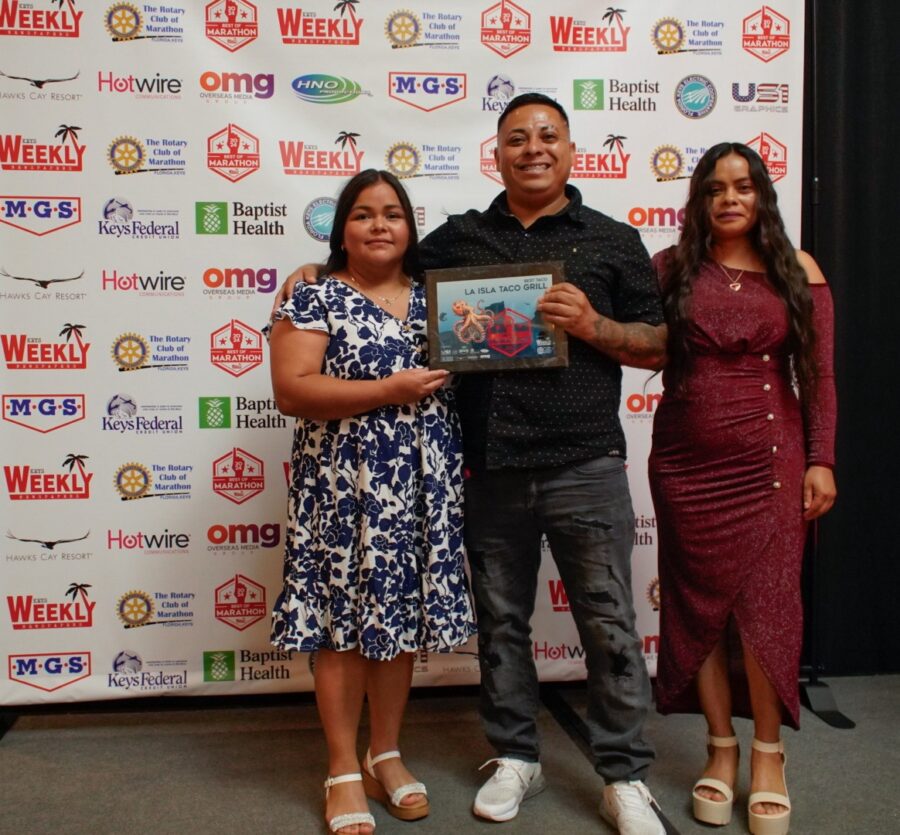 a man and two women standing in front of a sign