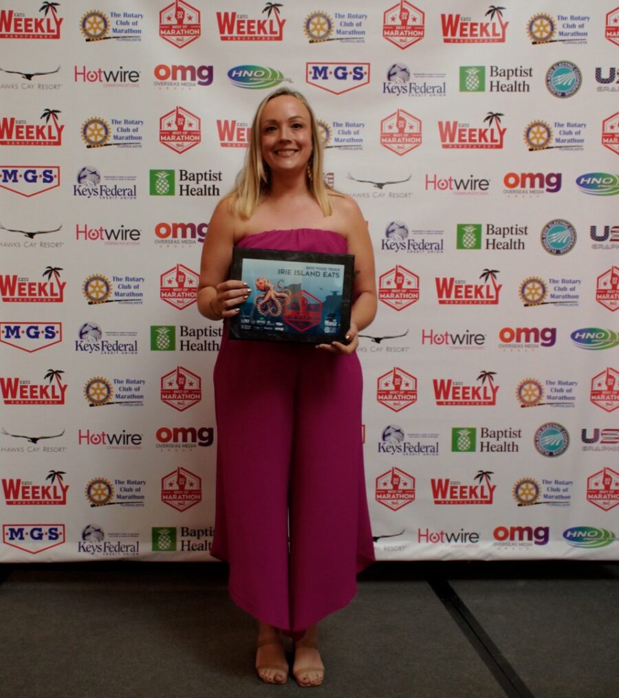 a woman standing in front of a wall holding a plaque