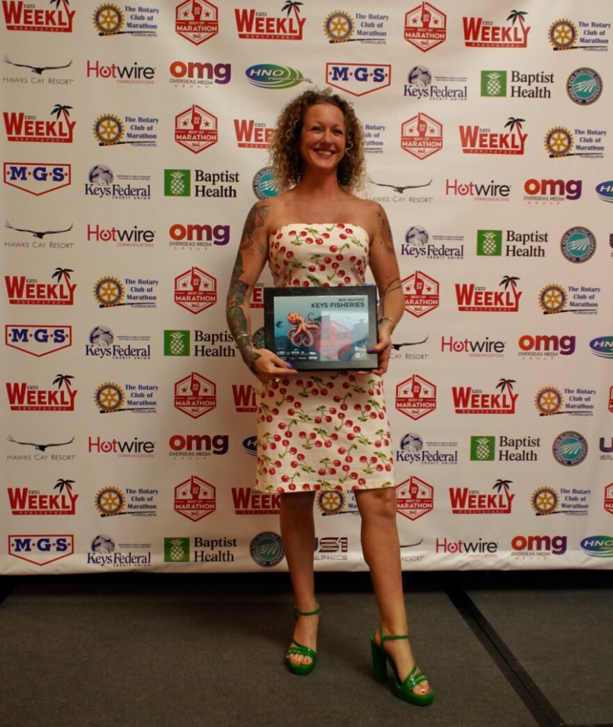 a woman standing in front of a wall holding an award