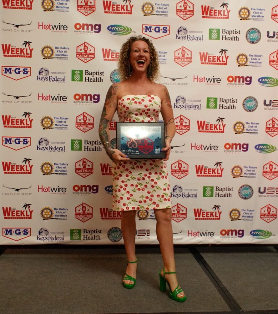 a woman standing in front of a wall holding an award