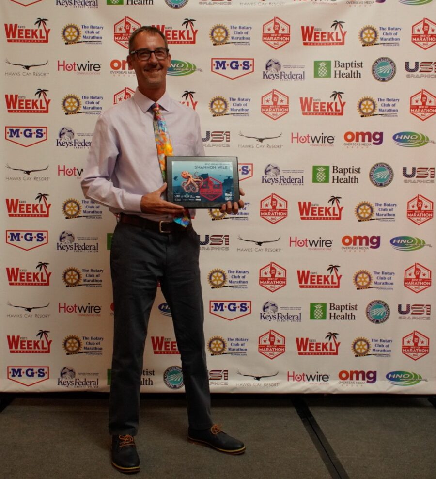 a man standing in front of a wall holding an award