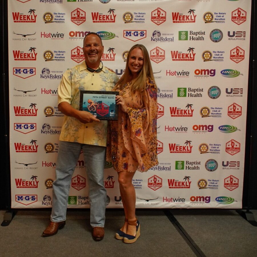 a man standing next to a woman holding a plaque