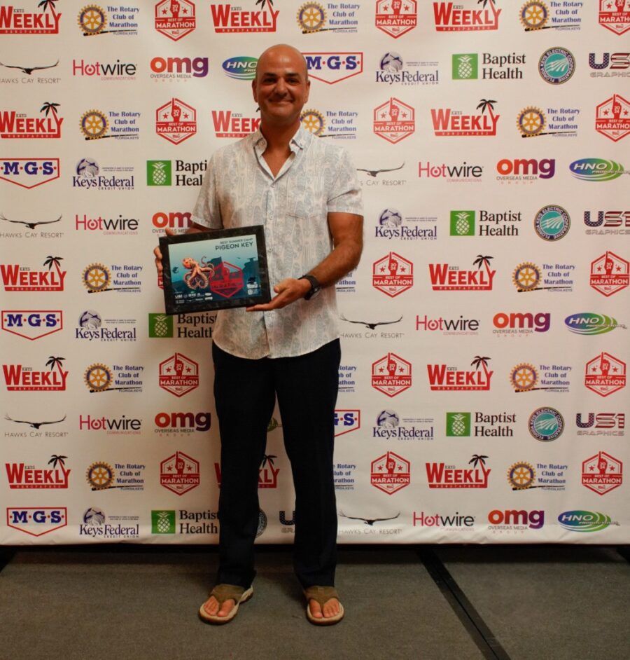 a man standing in front of a wall holding a plaque