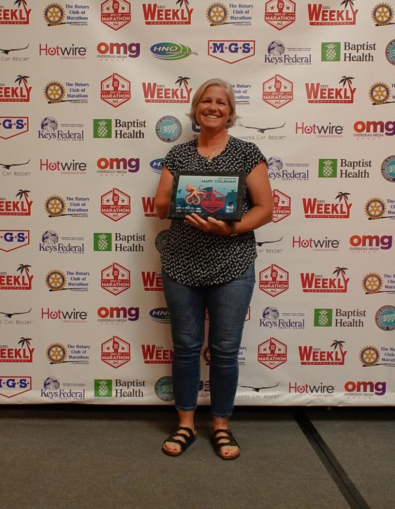 a woman standing in front of a wall holding a book