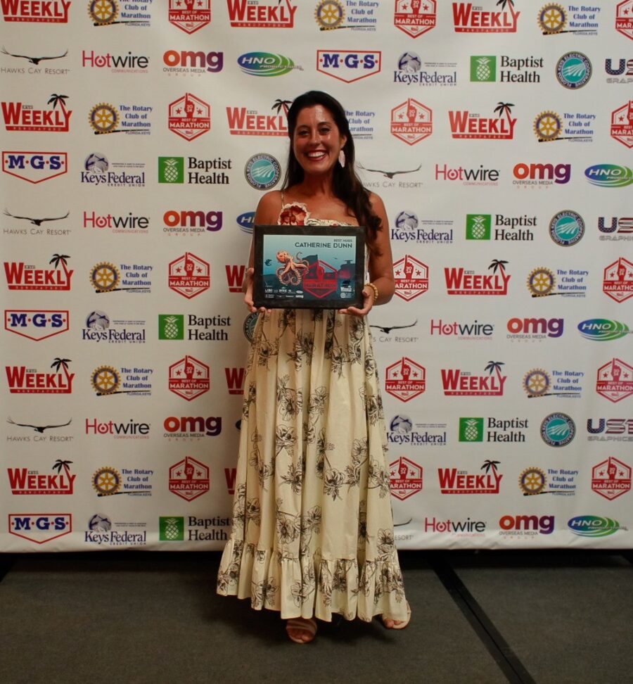 a woman standing in front of a wall holding a plaque