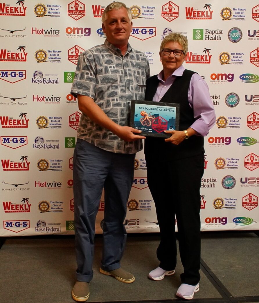 a man standing next to a woman holding a plaque