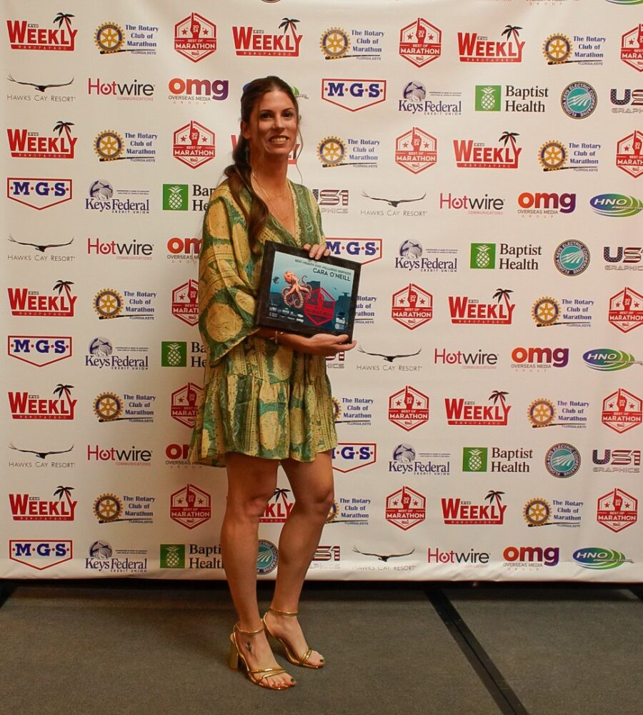 a woman standing in front of a wall holding a plaque