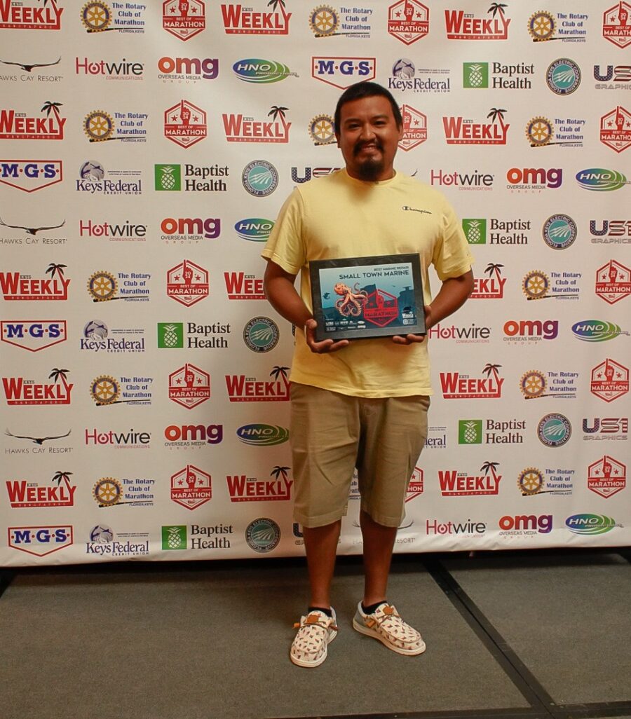 a man standing in front of a wall holding a plaque