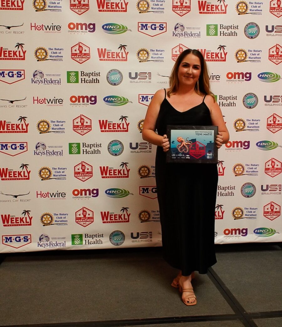 a woman standing in front of a wall holding a book