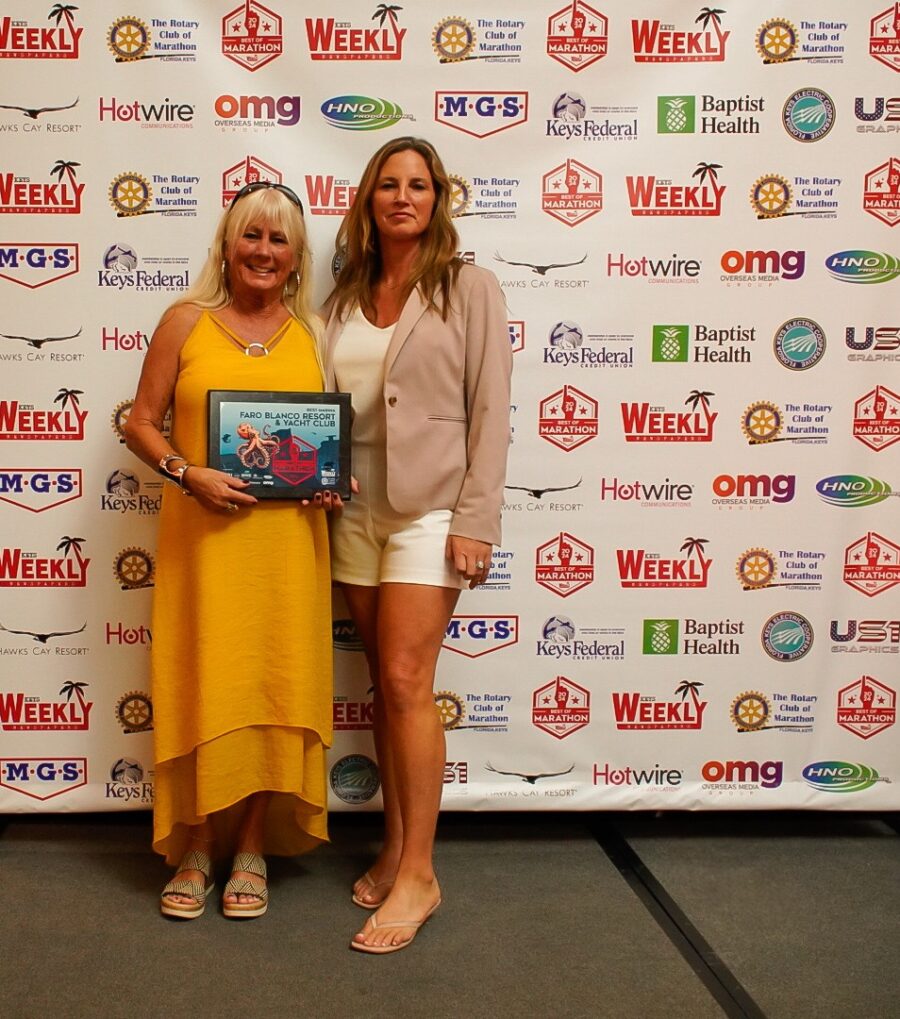 two women standing next to each other holding a plaque