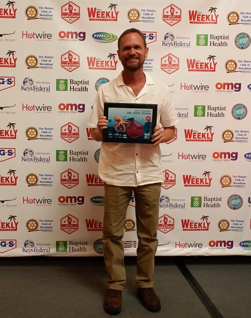 a man standing in front of a wall holding a plaque