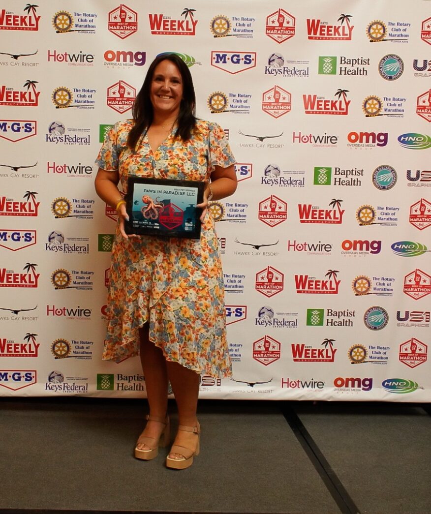 a woman standing in front of a wall holding a plaque