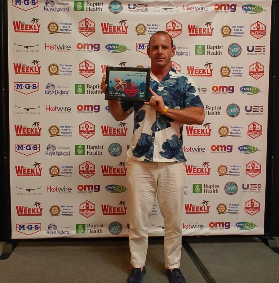 a man standing in front of a wall holding an award