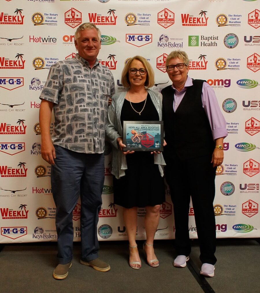 two women and a man standing in front of a sign